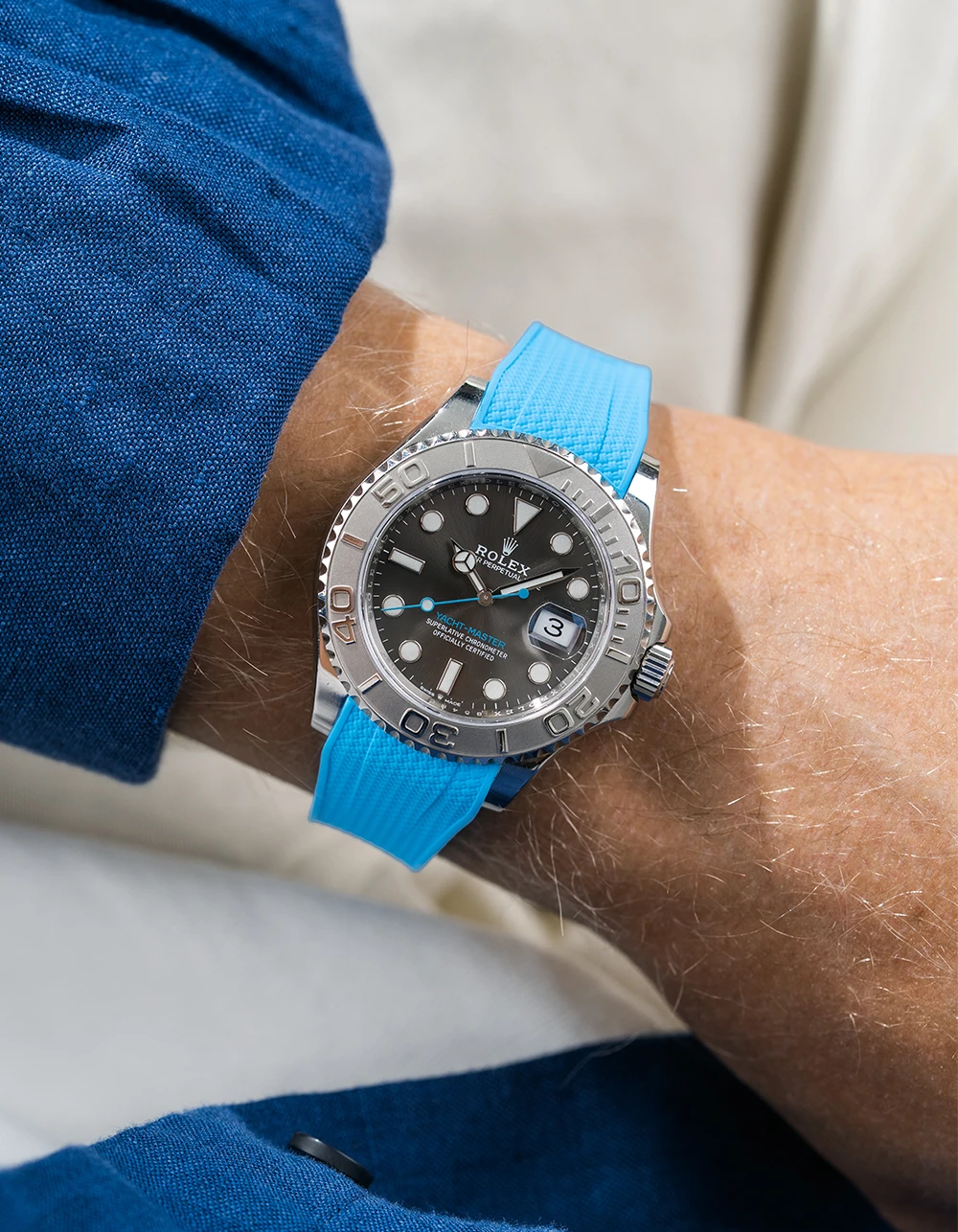 Close-up of a person wearing a Rolex YachtMaster 2 126622 / 116622 model watch with a blue shirt sleeve and a Capri Blue Vertech FKM rubber watch strap from Wristbuddys