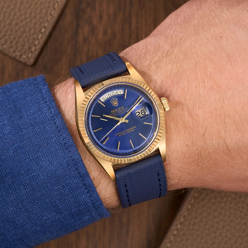 Rolex Day-Date with a blue straight end watch strap worn on a wrist, paired with a blue shirt.