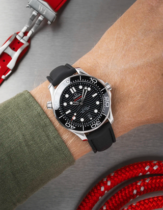 Black Omega Seamaster with a detailed face on a person's wrist, with a blurred background