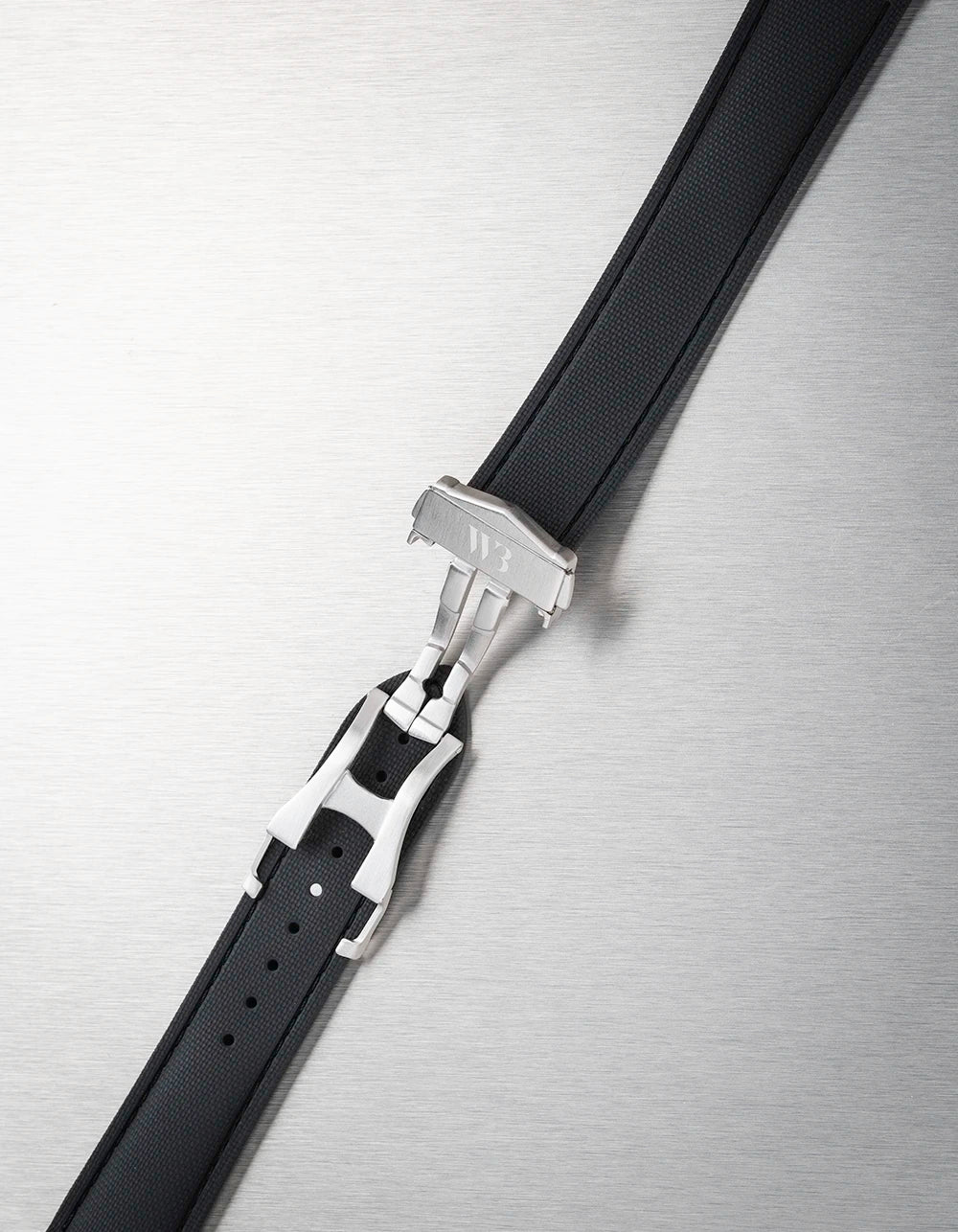 Black leather belt with silver buckle on a metallic surface