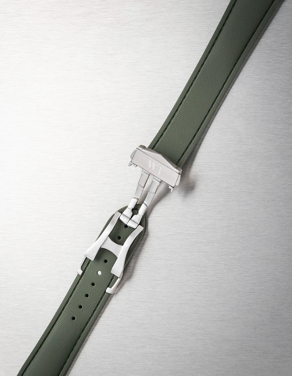Close-up of a black watch strap with a silver buckle on a metallic background