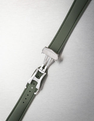 Close-up of a black watch strap with a silver buckle on a metallic background