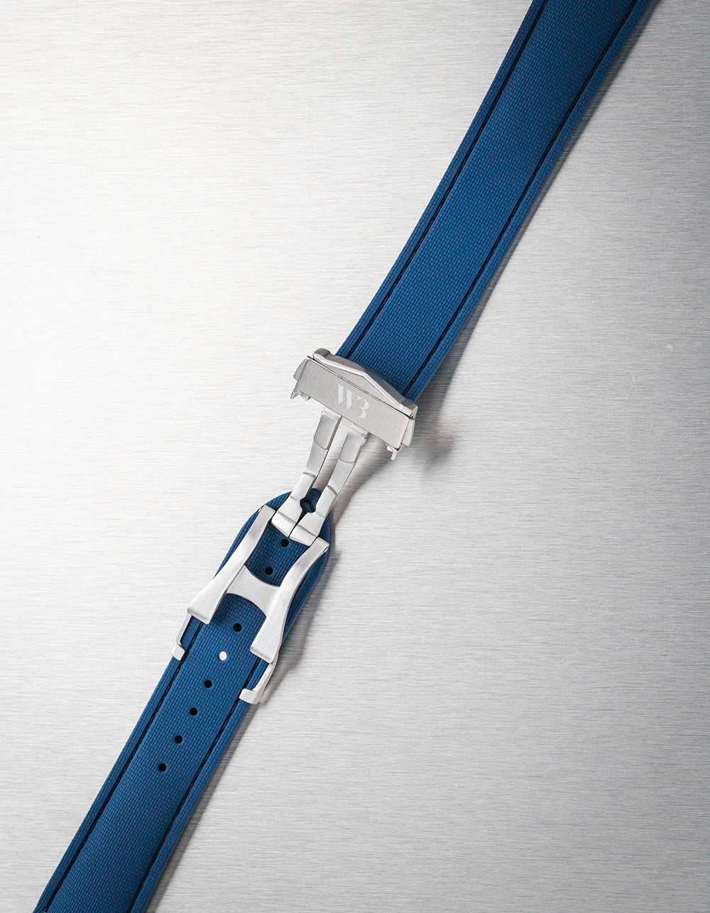 Close-up of a blue watch strap with silver buckle on a metallic surface