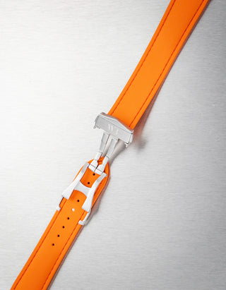 Orange watch strap with silver clasp on a textured gray background
