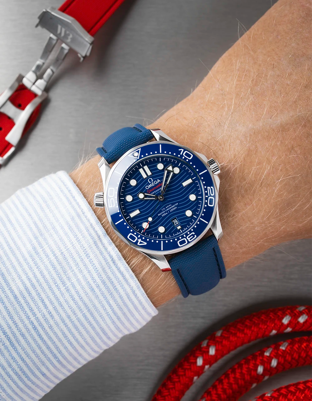 Wrist wearing a blue Omega Seamaster Diver 300 with a detailed face on a wrist with a white sleeve.