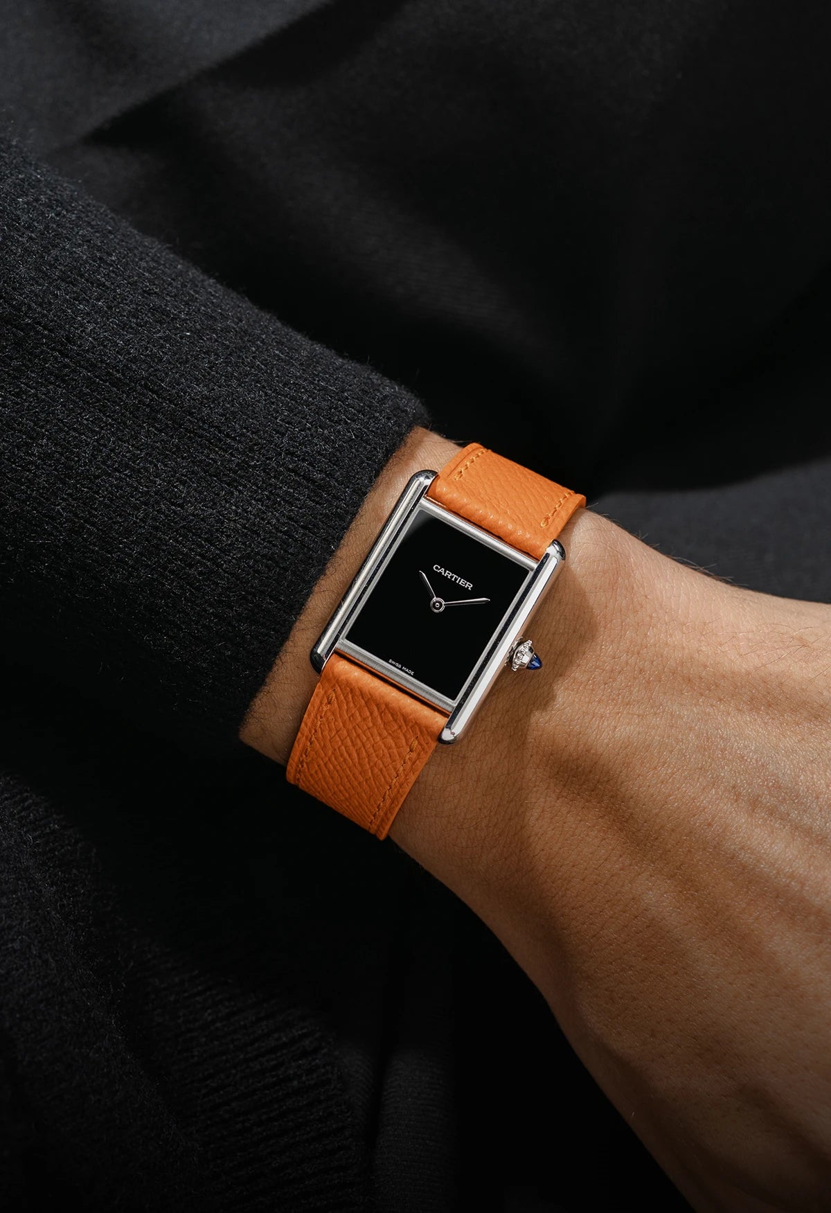 Wrist shot with a leather strap on a Cartier watch with a black shirt and black background