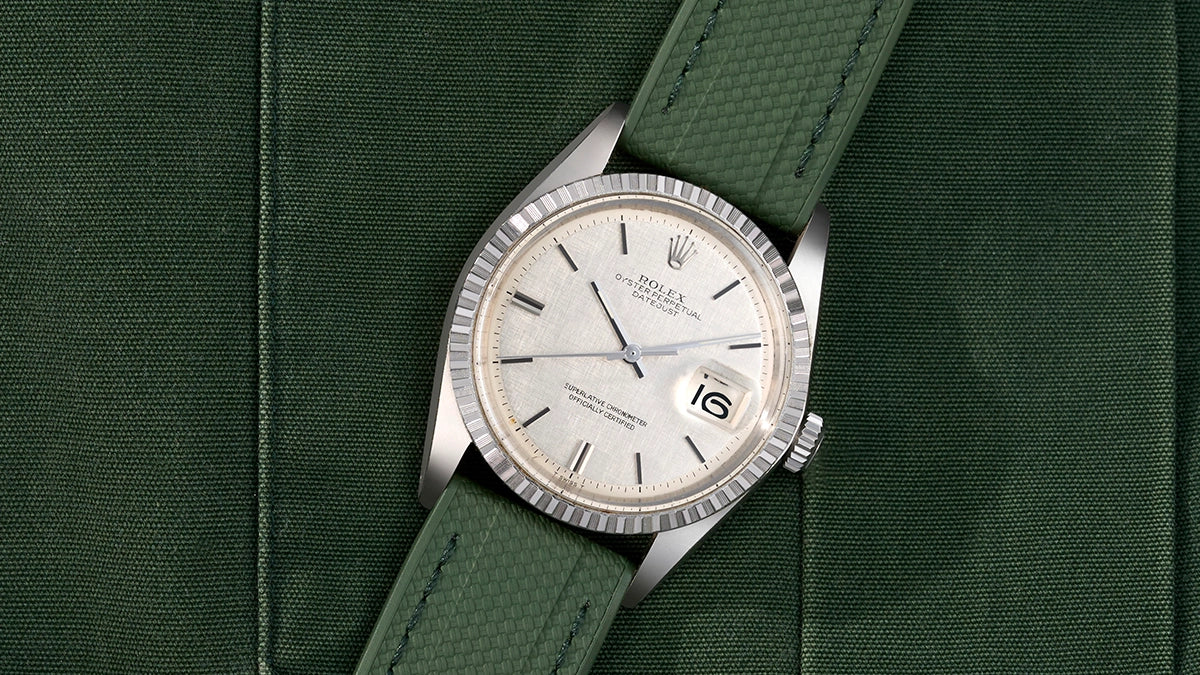 Rolex Datejust with a green straight end watch strap on a matching green fabric background.