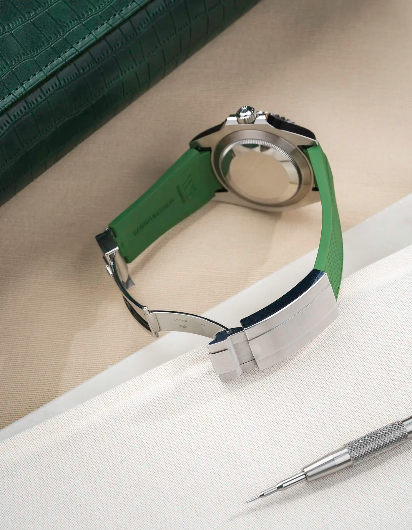 Back view product photo of Rolex Submariner 41 with green Classic Smooth FKM Rubber Strap sitting on the watch, integrated with original clasp – clasp open and watch case visible