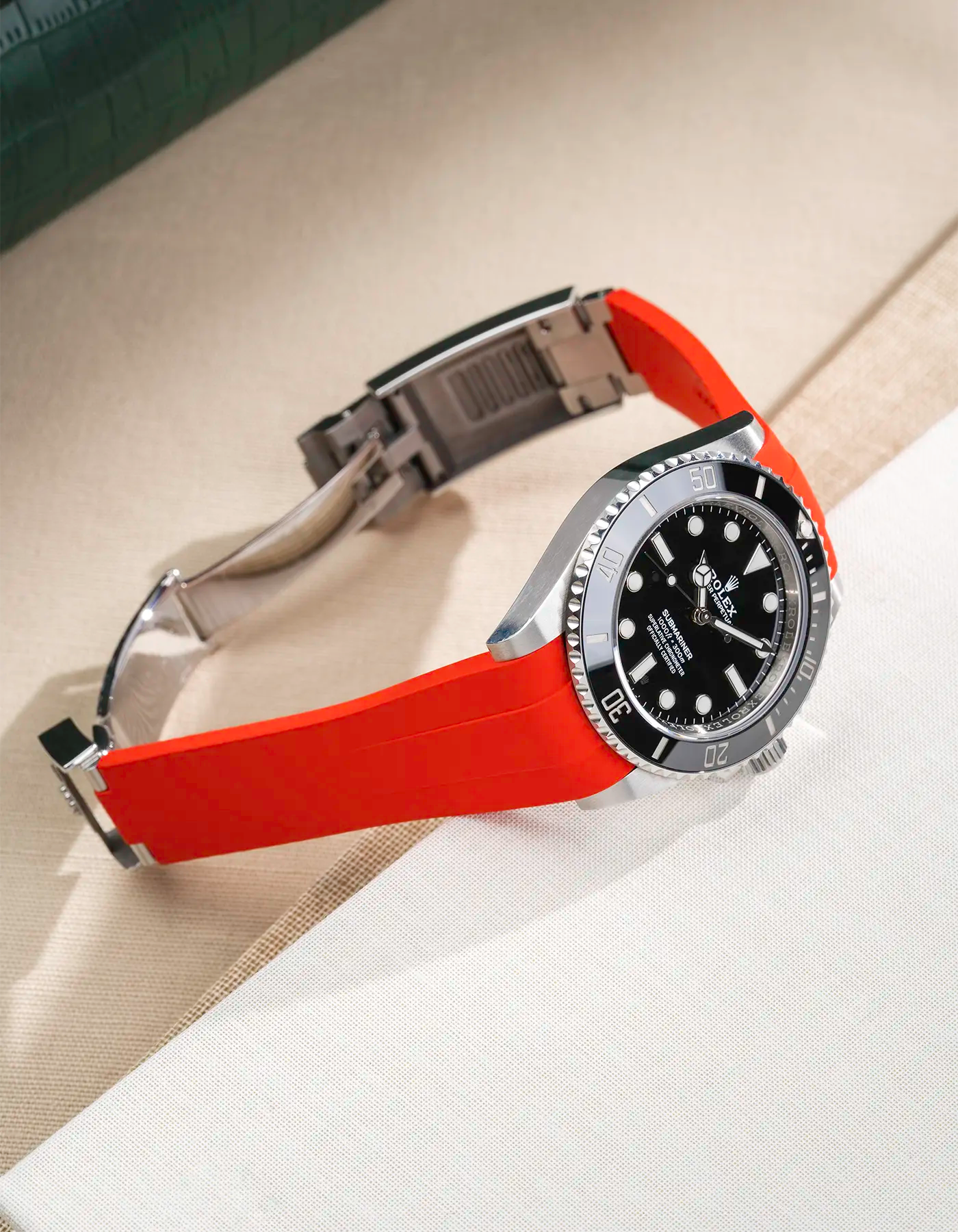 Lifestyle product photo of Rolex Submariner 41 with red Classic Smooth FKM Rubber Strap attached to the watch, integrated with original clasp – side angle view, clasp open