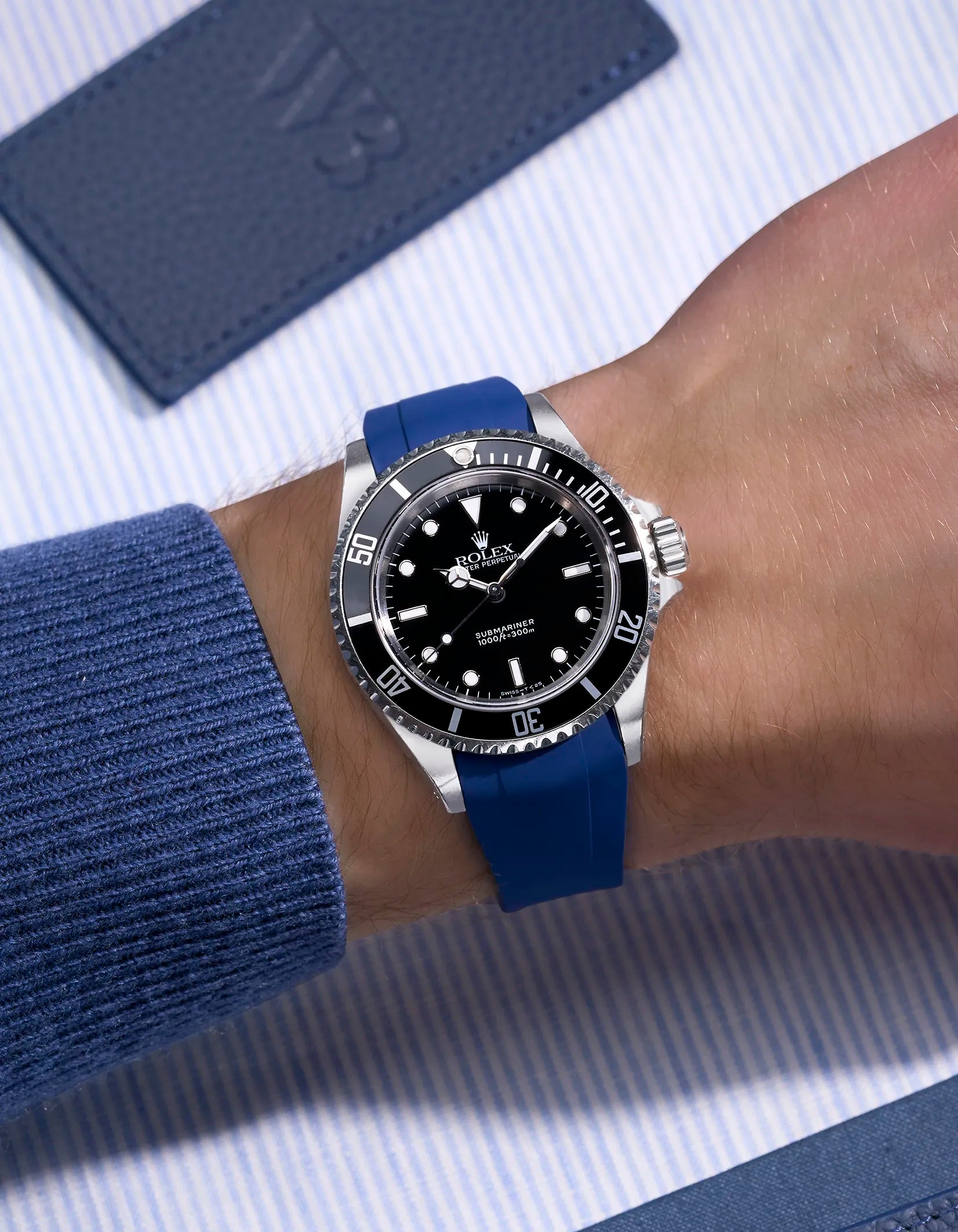 Blue rubber strap integrated with original Rolex clasp on Submariner 16610/14060 – wrist view on blue background