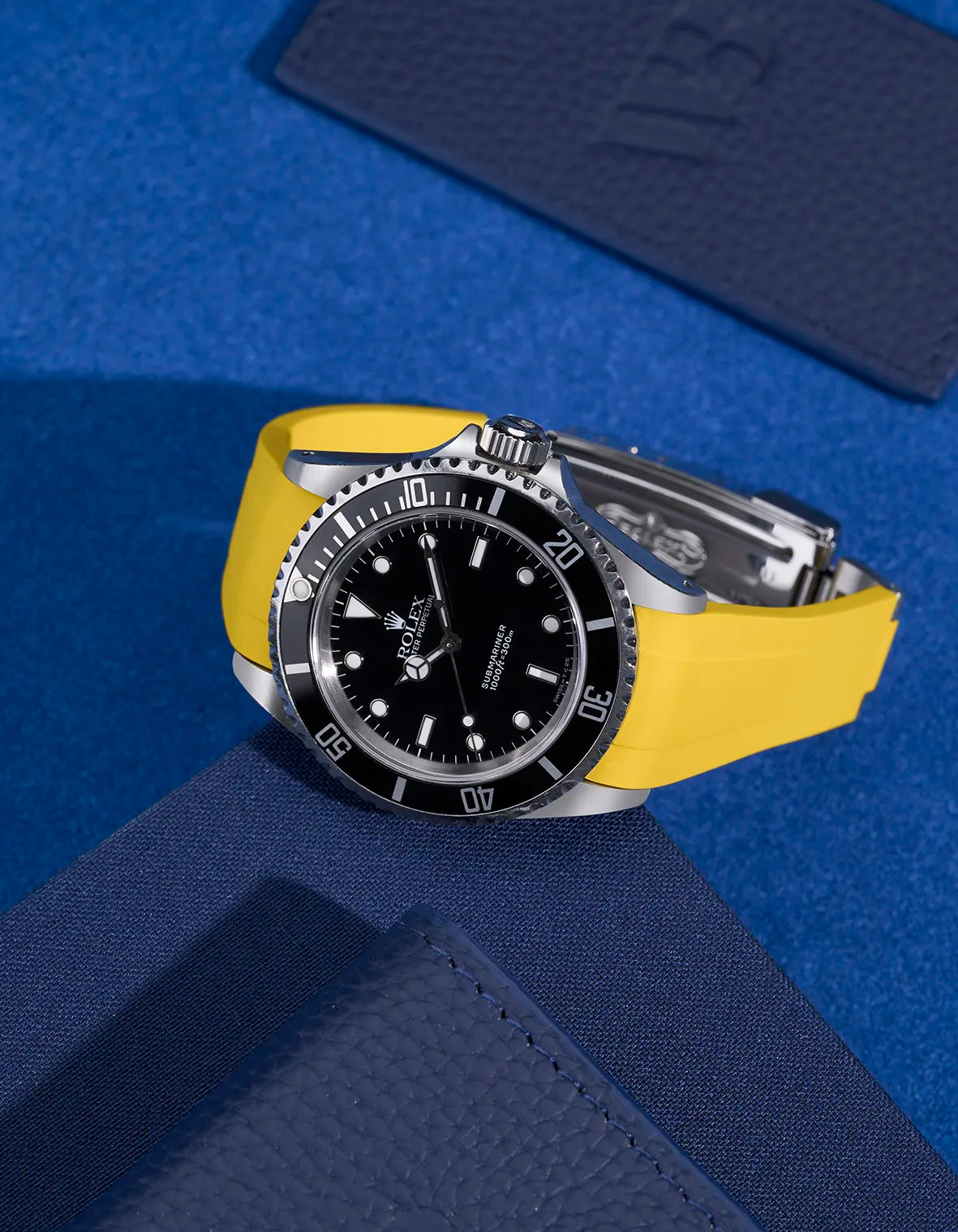 Rolex Submariner 16610 and 14060 with yellow FKM rubber strap and original clasp – styled on dark blue accessories