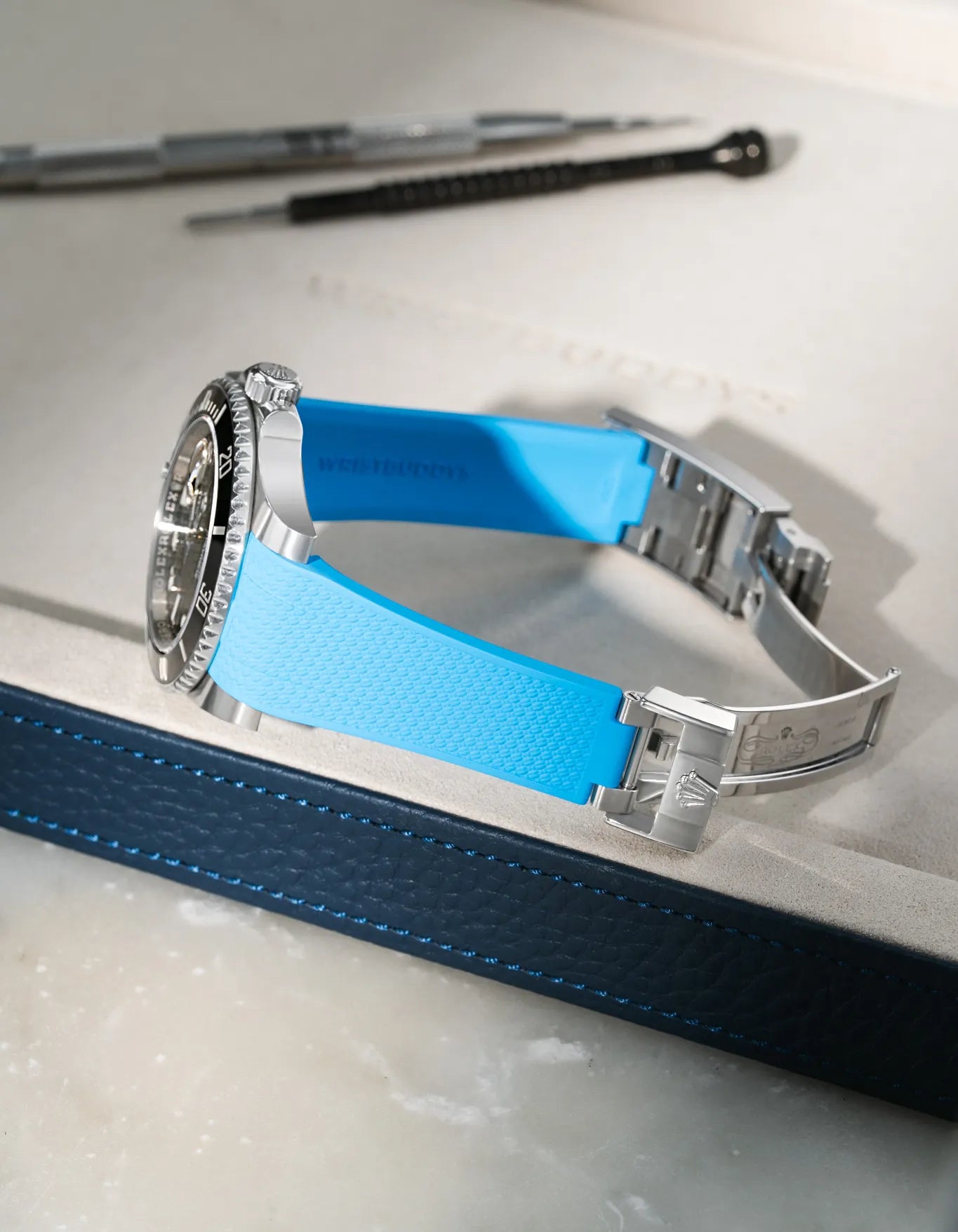 Capri Blue integrated FKM rubber watch strap for Rolex Submariner 126610/116610, Vertech textured finish, fits original clasp on a grey valet tray.