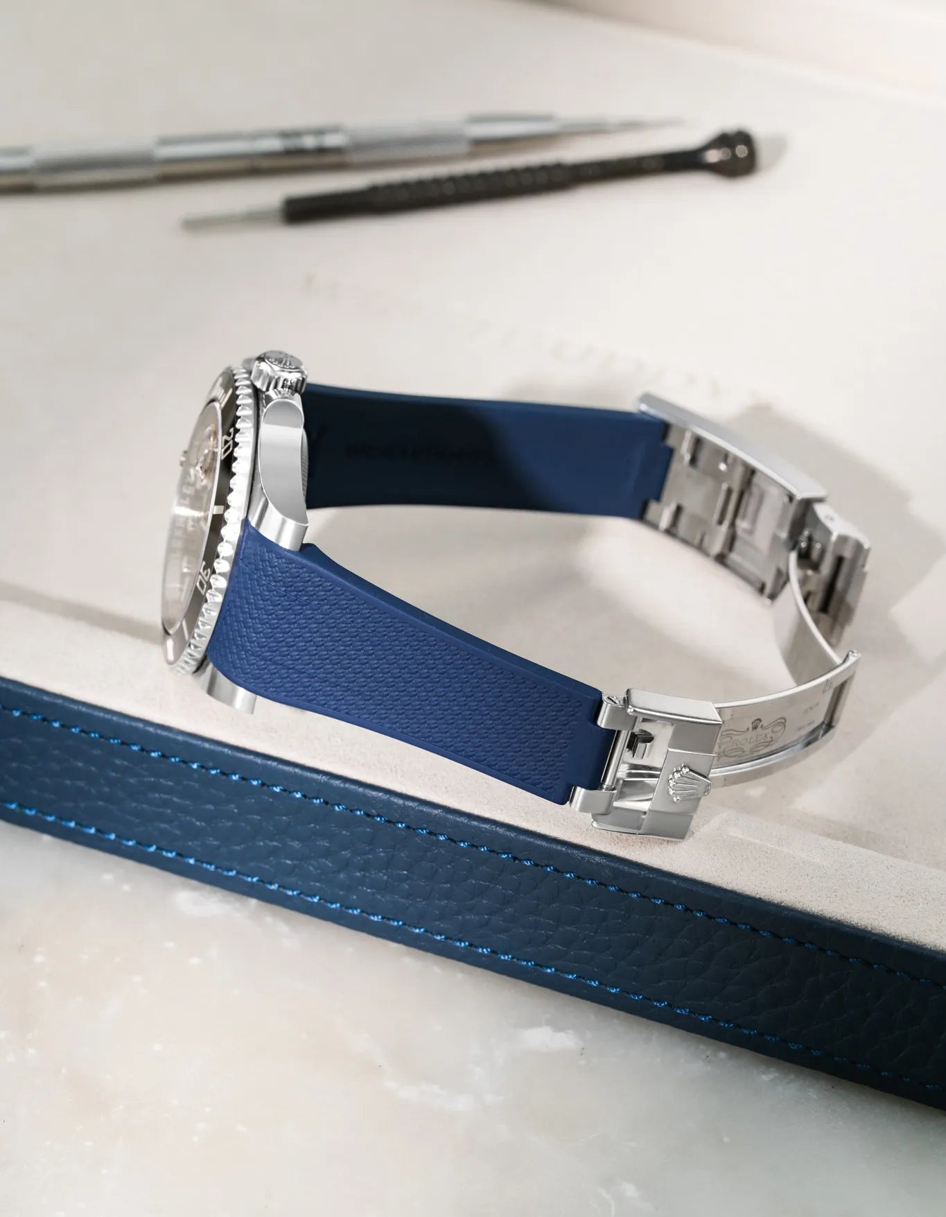 Navy blue Vertech FKM rubber strap for Rolex Submariner 116610 and 126610, integrated fit for original clasp, resting on a blue leather valet tray.