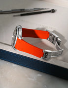 Red Vertech FKM rubber strap for Rolex Submariner 116610 and 126610, integrated fit for original clasp, resting on a leather valet tray