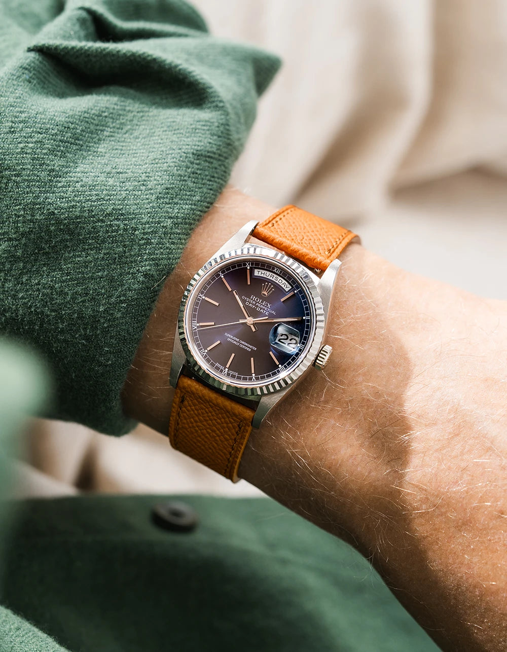 Rolex DayDate in white gold with a brown epsom leather watch strap from Wristbuddys on a wrist, wearing green sleeve.