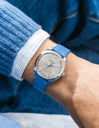 Grand Seiko with a  ocean blue suede leather strap from Wristbuddys on a wrist, wearing a blue sleeve.