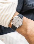 Grand Seiko with a black epsom leather watch strap from Wristbuddys on a wrist, wearing a beige sleeve.