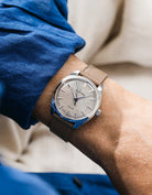 Grand Seiko with a taupe calfskin leather watch strap from Wristbuddys on a wrist, wearing a blue shirt.
