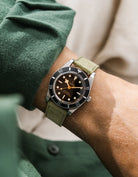 A Tudor BB54 with a herb green suede leather strap from Wristbuddys on a wrist, wearing a blue sleeve.