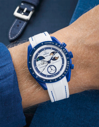 MoonSwatch Mission to Earthphase – Moonshine Gold with white rubber strap and blue stitching, wrist shot over blue background