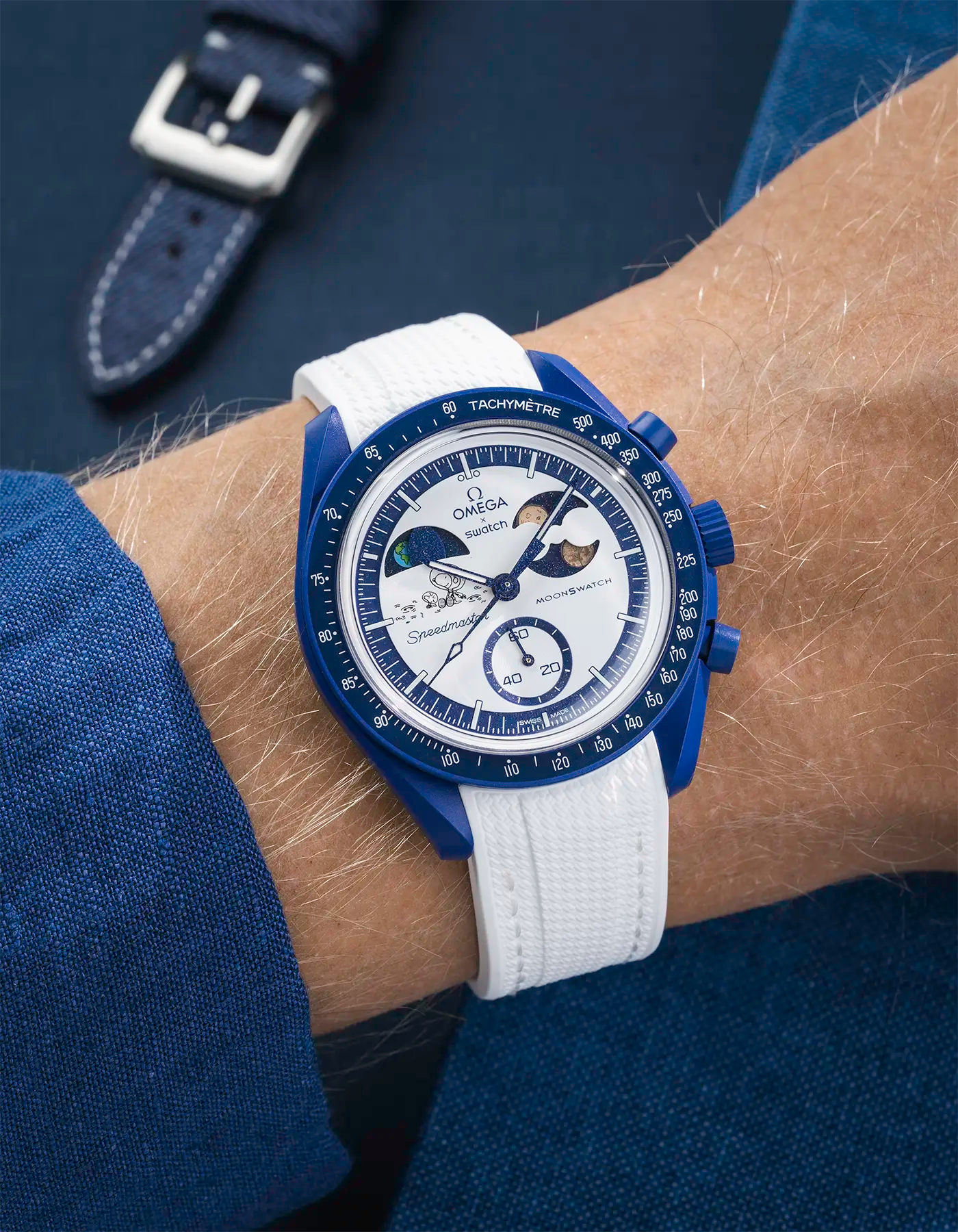 MoonSwatch Mission to Earthphase – Moonshine Gold with white rubber strap, wrist shot over blue background