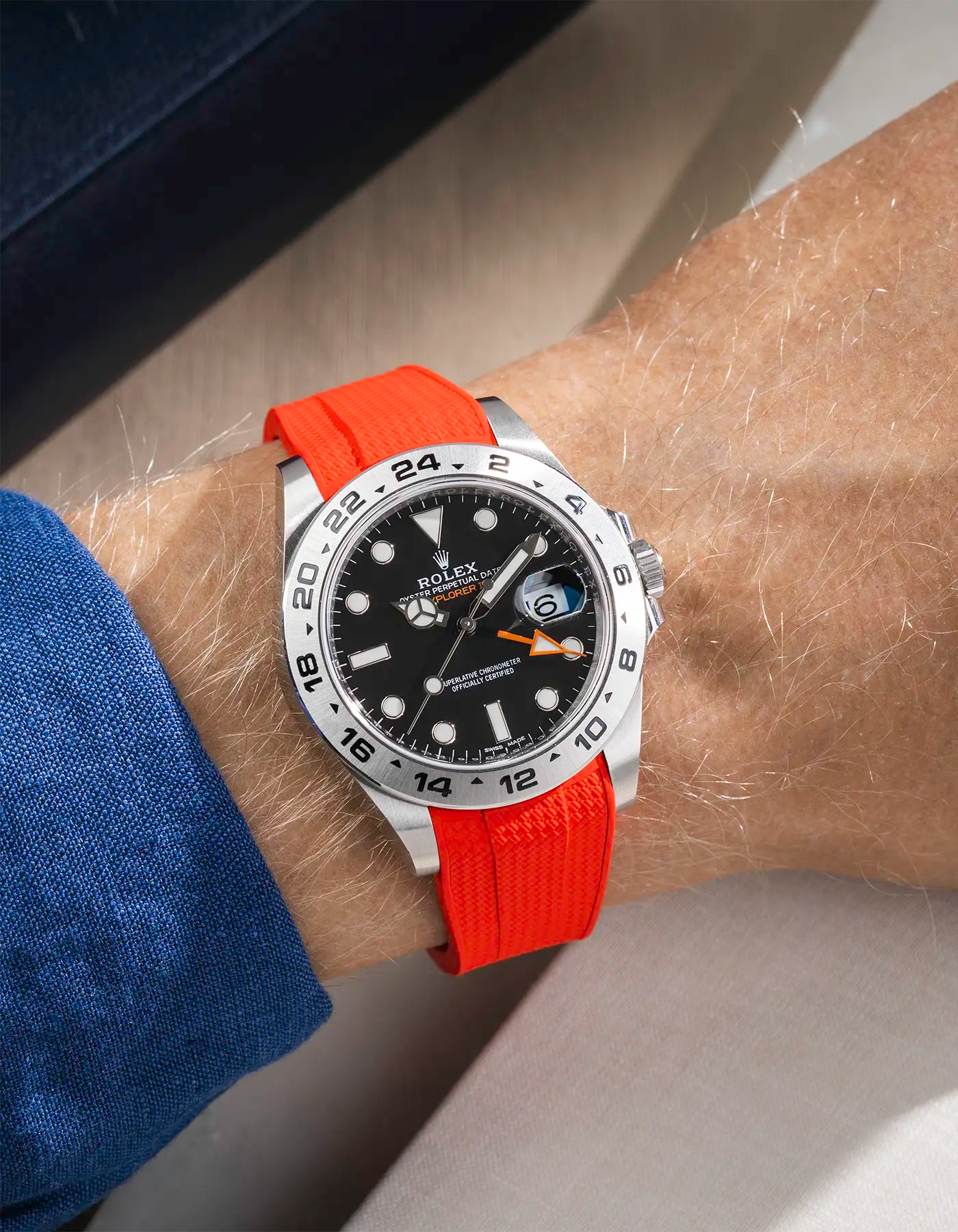 Wrist shot on Red Vertech FKM Rubber Strap Integrated with Original Clasp - Rolex Explorer 216570 over a table with a watch roll