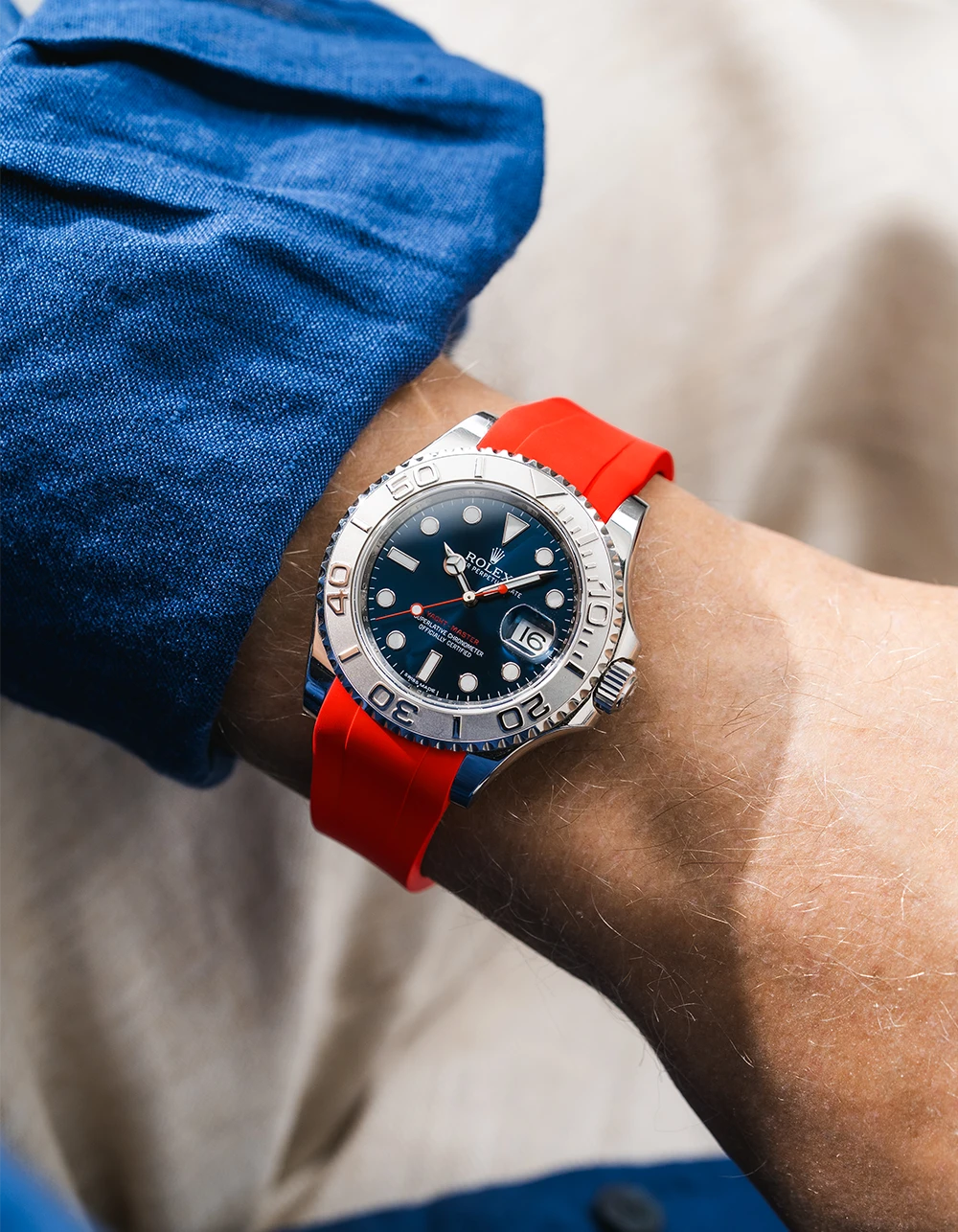 Close-up of a person wearing a Rolex YachtMaster 2 126622 / 116622 model watch with a dark blue shirt sleeve and a red FKM rubber watch strap from Wristbuddys