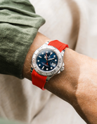 Close-up of a person wearing a Rolex YachtMaster 2 126622 / 116622 model watch with a dark green shirt sleeve and a red vertech FKM rubber watch strap from Wristbuddys