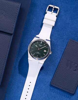 Tissot PRX Powermatic 80 with white FKM rubber strap on blue textured background flat lay