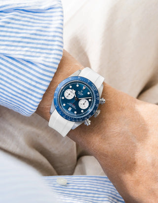 Wristbuddys white rubber strap on Tudor Black Bay Chrono — wrist lifestyle shot with striped shirt and beige trousers