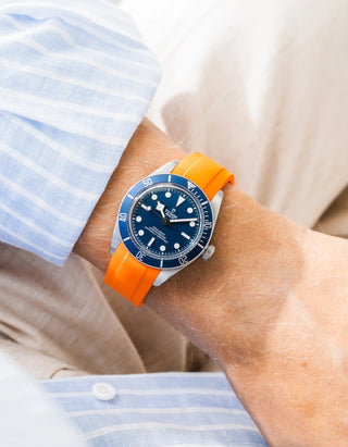 Wristbuddys orange rubber strap on Tudor Black Bay 58 Navy Blue — wrist lifestyle shot with striped shirt