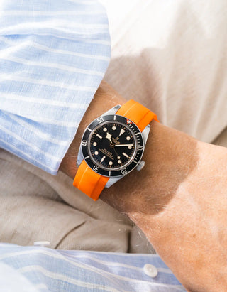 Wristbuddys orange rubber strap on Tudor Black Bay 58 Black — wrist lifestyle shot with striped shirt