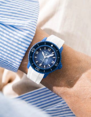 White rubber strap for Blancpain x Swatch Scuba Fifty Fathoms Atlantic Ocean – worn on wrist with light blue striped shirt, dark blue dial and dark blue bezel with dark blue case, side angle view