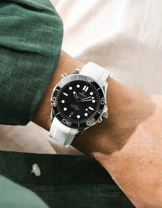 White rubber strap for Omega Seamaster Diver 300 42mm – worn on wrist with dark green linen jacket, black dial and bezel, front angle view