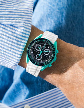 White rubber strap for OMEGA x Swatch MoonSwatch Mission On Earth – Polar Lights, worn on the wrist in a lifestyle shot with clothing visible