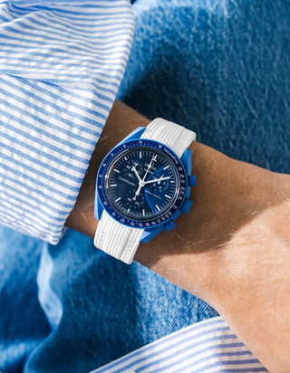 White rubber strap fitted to an OMEGA x Swatch MoonSwatch Mission to Neptune watch, worn on the wrist in a lifestyle shot with clothing visible