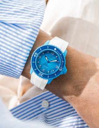 White Vertech rubber strap for Blancpain x Swatch Scuba Fifty Fathoms Blue Lagoon – worn on wrist with light blue striped shirt, blue dial and blue bezel with light blue case, side angle view