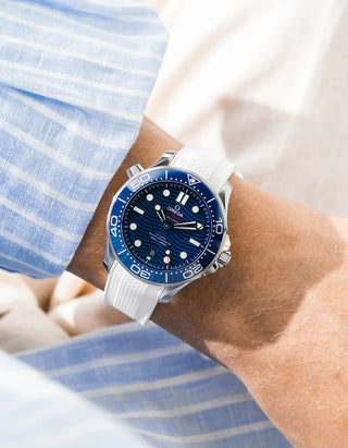White Vertech rubber strap for Omega Seamaster Diver 300 42mm – worn on wrist with light blue striped shirt, blue dial and bezel, low angle view