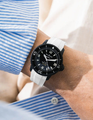 White Vertech rubber strap for Blancpain x Swatch Scuba Fifty Fathoms The Ocean of Storms – worn on wrist with light blue striped shirt, black dial and black bezel with black case, front angle view