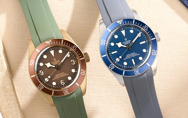 Two Tudor Black Bay 58 watches on beige fabric background one bronze with green rubber strap and one navy blue with grey rubber strap