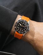 orange FKM rubber watch strap from Wristbuddys with a Tudor BB41 Heritage black dial on a person's wrist