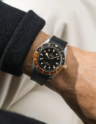 Tudor GMT two tone  watch on a person's wrist with a black FKM rubber watch strap from Wristbuddys and red accents on the bezel