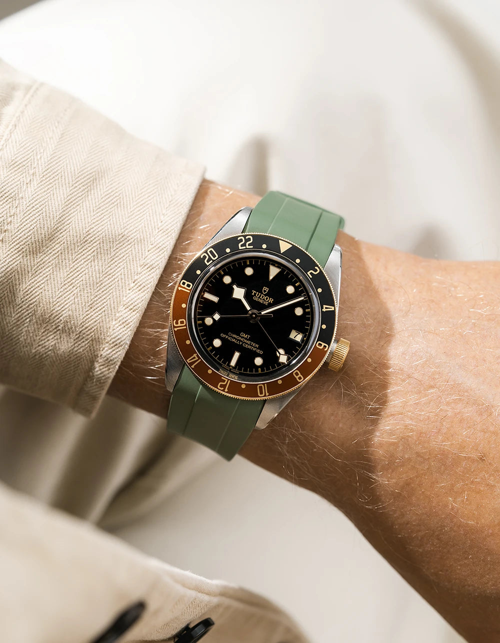 Tudor GMT two tone watch on a person's wrist with a green FKM rubber watch strap from Wristbuddys and brown accents on the bezel