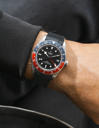 Tudor GMT watch on a person's wrist with a black FKM rubber watch strap from Wristbuddys and red accents on the bezel