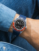 Tudor GMT watch on a person's wrist with a navy blue FKM rubber watch strap from Wristbuddys and red accents on the bezel