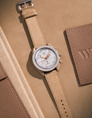 Flat lay of Omega X Swatch Mission to Jupiter with Beige suede leather strap, styled with neutral and warm brown accessories