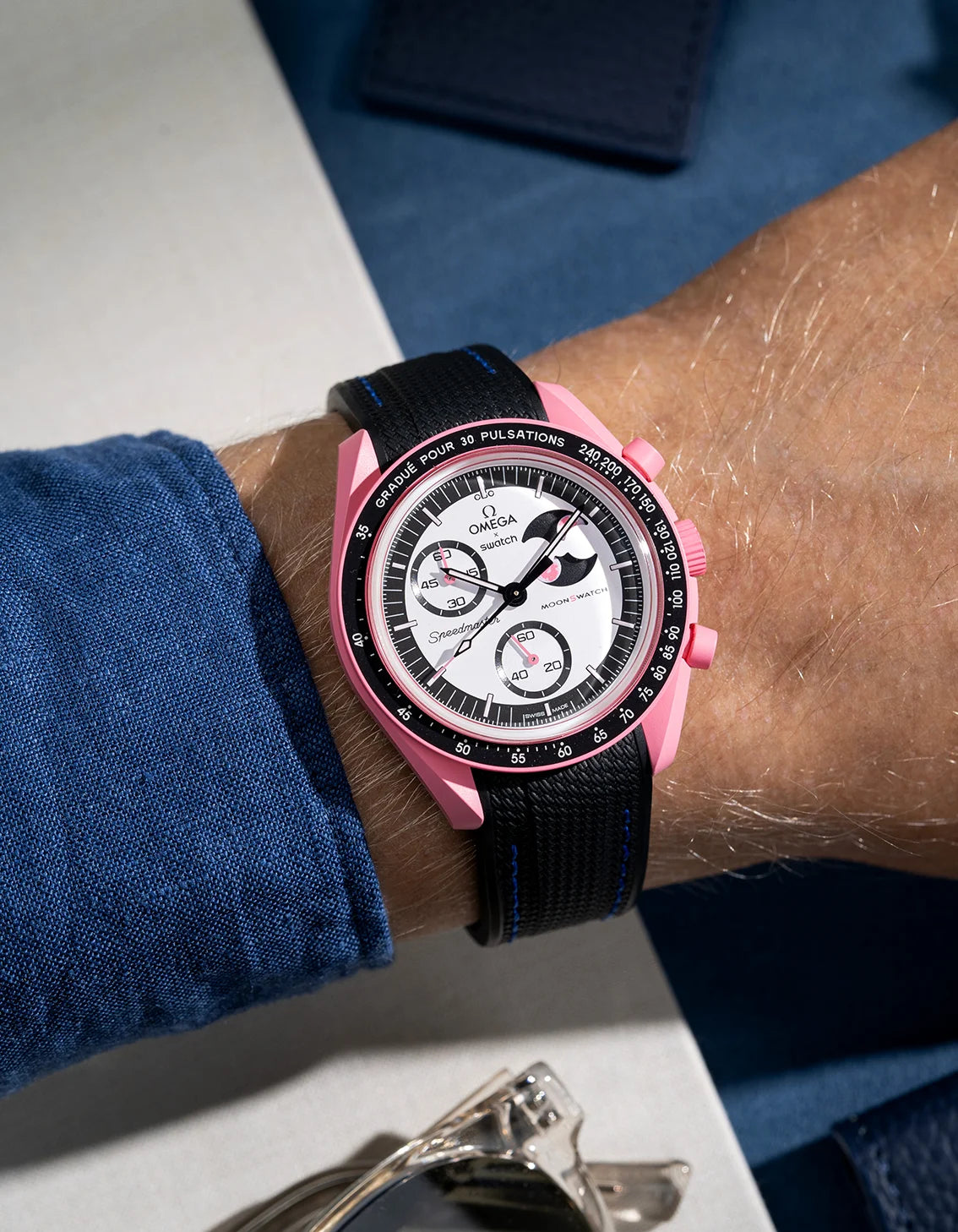 Black curved vertech rubber strap with blue stitches on MoonSwatch Mission to The Pink Moonphase wrist shot