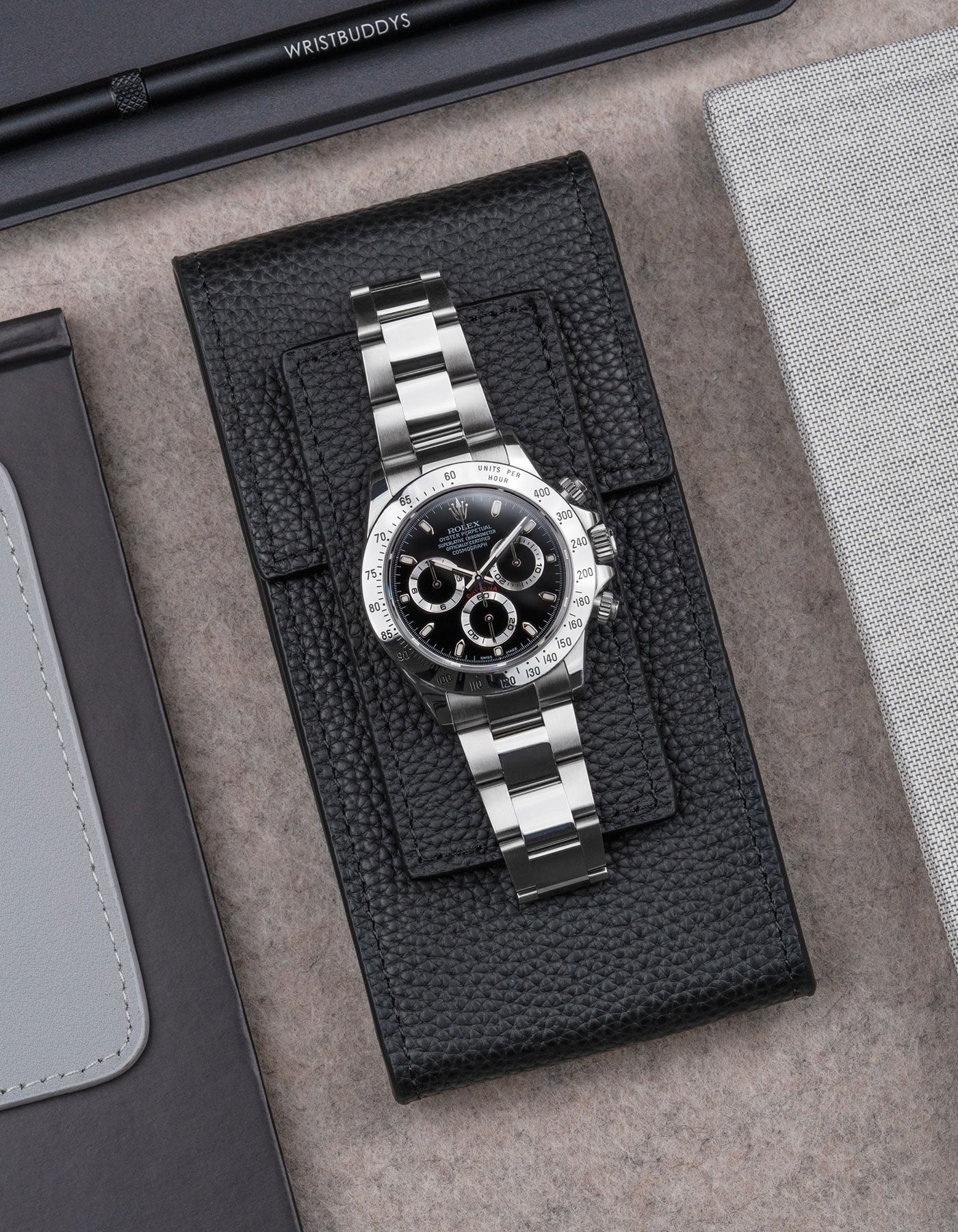 Rolex Daytona displayed on Black leather watch pouch by Wristbuddys – elegant flat lay product photo of luxury watch case