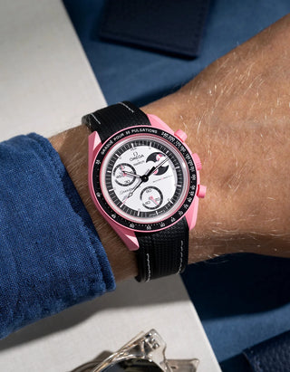 Wrist shot showing black rubber strap with white stitching for Omega X Swatch MoonSwatch Mission to the Pink Moonphase