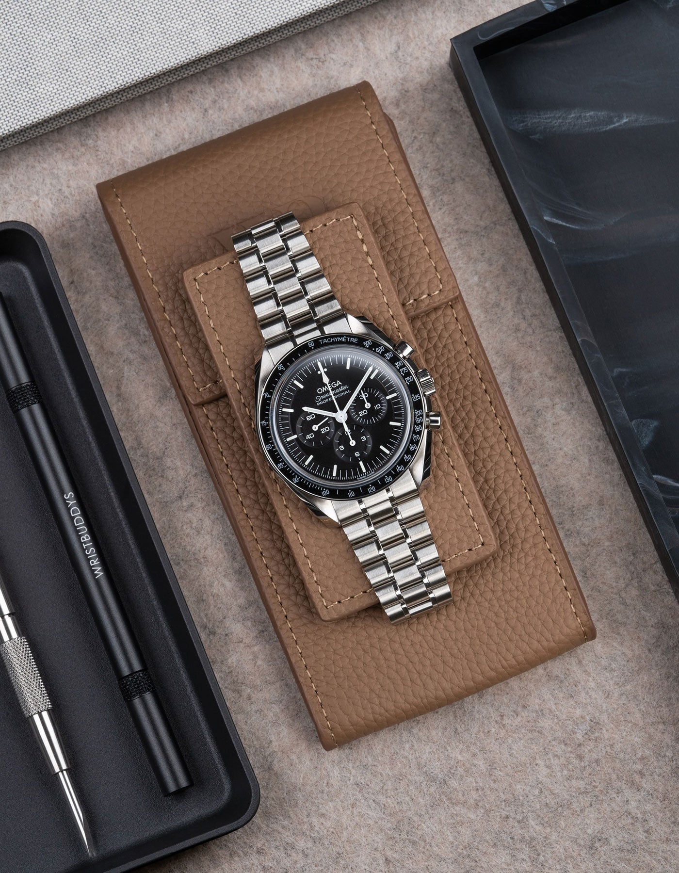 Omega Speedmaster displayed on Brown leather watch pouch by Wristbuddys – elegant flat lay product photo of luxury watch case